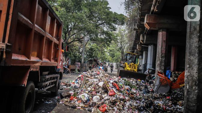 Petugas PPSU menggunakan kendaraan alat berat untuk mengangkut tumpukan sampah di kolong tol Wiyoto Wiyono, Tanjung Priok, Jakarta, Selasa (5/11/2019). Dalam sehari, petugas mengangkut sampah hingga 10 truk dengan berat total sekitar 100 ton ke TPA Bantar Gebang. (Liputan6.com/Faizal Fanani)