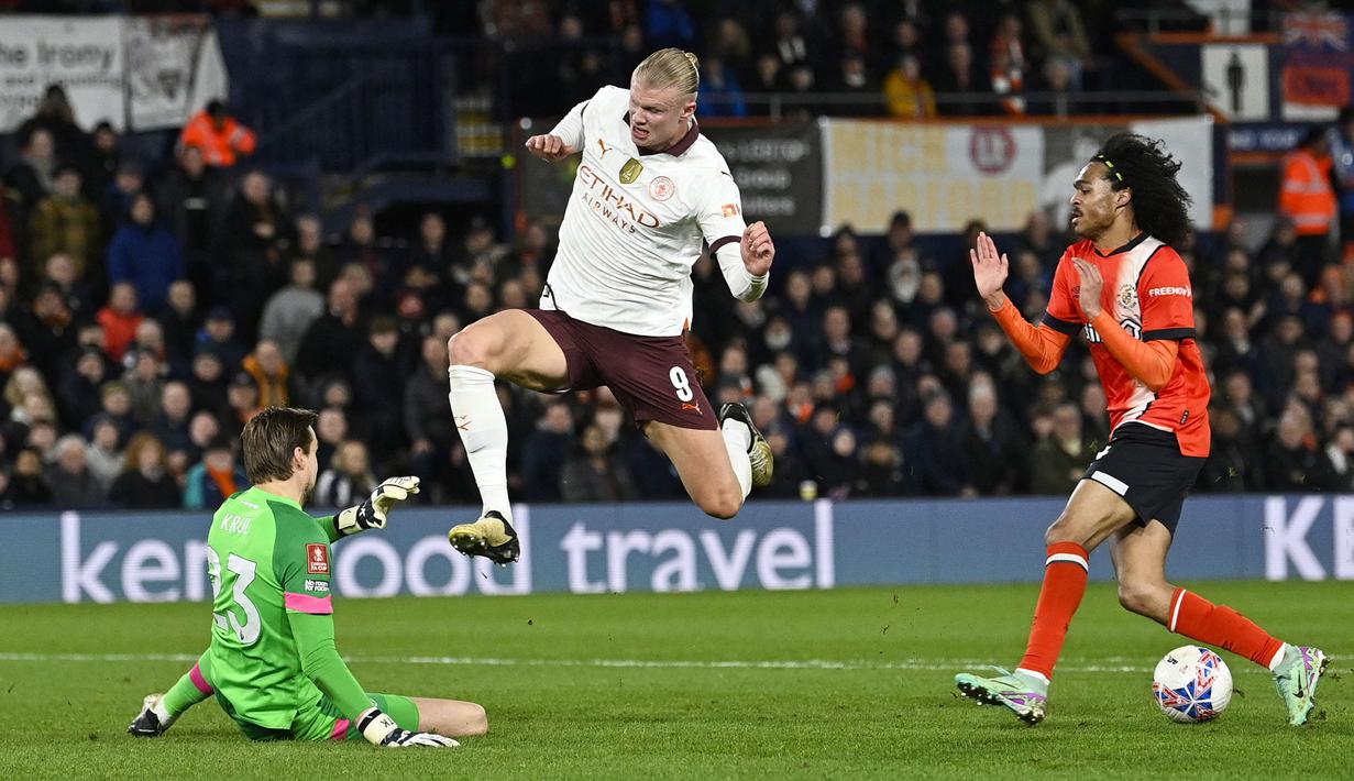 Pemain Manchester City, Erling Haaland (tengah) berusaha mencetak gol dihalau kiper Luton Town, Tim Krull pada laga putaran kelima Piala FA 2023/2024 yang berlangsung di Kenilworth Road Stadium, Luton, Inggris, Rabu (28/02/2024) dini hari WIB. (AFP/Justin Tallis)