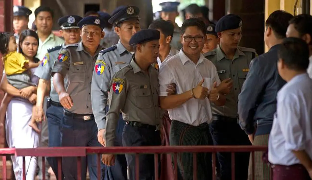 Wartawan Reuters, Wa Lone (tengah) dikawal oleh polisi setibanya di pengadilan distrik Yangon, Myanmar, Senin (3/9). Dua jurnalis Reuters dituduh melanggar undang-undang rahasia negara saat menyelidiki kekerasan terhadap Rohingya. (AP/Thein Zaw)