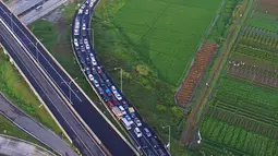 Pandangan udara kendaraan terjebak kemacetan saat keluar tol Pejagan, Jawa Tengah, Sabtu (2/7). Kemacetan panjang hingga 18 km terjadi dikarenakan antrean saat pembayaran pintu tol keluar. (Liputan6.com/Balgo Marbun)