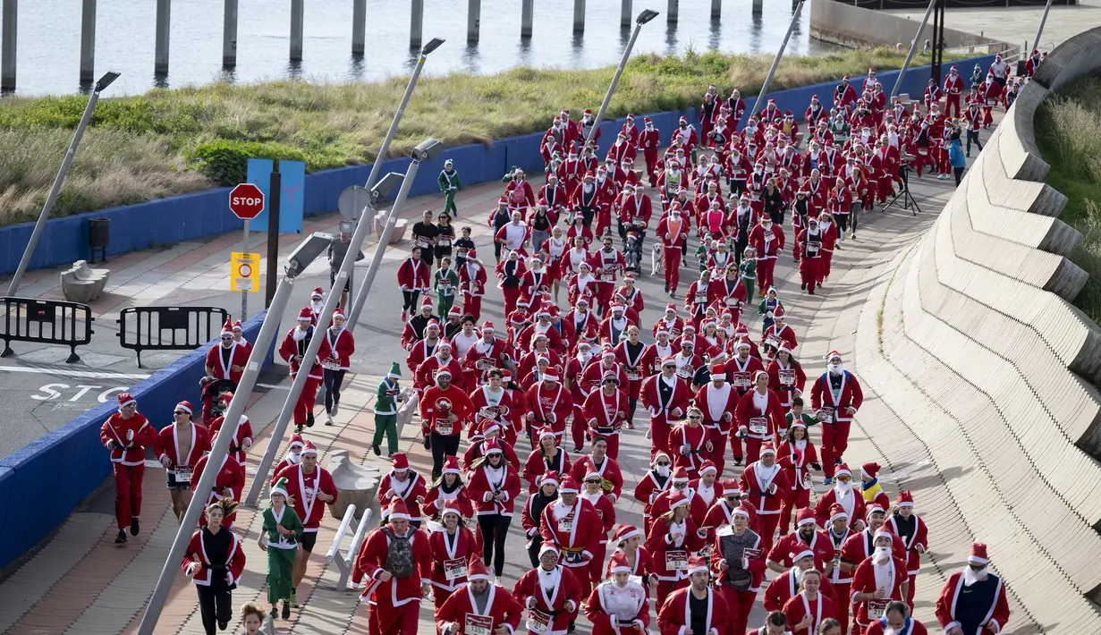 Sejumlah pelari berkostum Sinterklas berlomba dalam acara fun run 5 km di jalanan Barcelona, Spanyol pada Minggu (22/12/2024) waktu setempat. (AFP/Josep Lago)