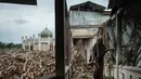 Seorang siswi berjalan di atas bangku untuk menghindari lumpur karena tumpukan pohon tumbang yang tersapu banjir bandang masih berada di Pesantren Darul Mukhlisin dan masjid yang terhubung dengannya di Aceh Tamiang, pada Minggu 14 Desember 2025. Pemandangan memprihatinkan masih terlihat di Pondok Pesantren Darul Mukhlisin, Aceh Tamiang, Minggu (14/12/2025). (Yasuyoshi Chiba/AFP)