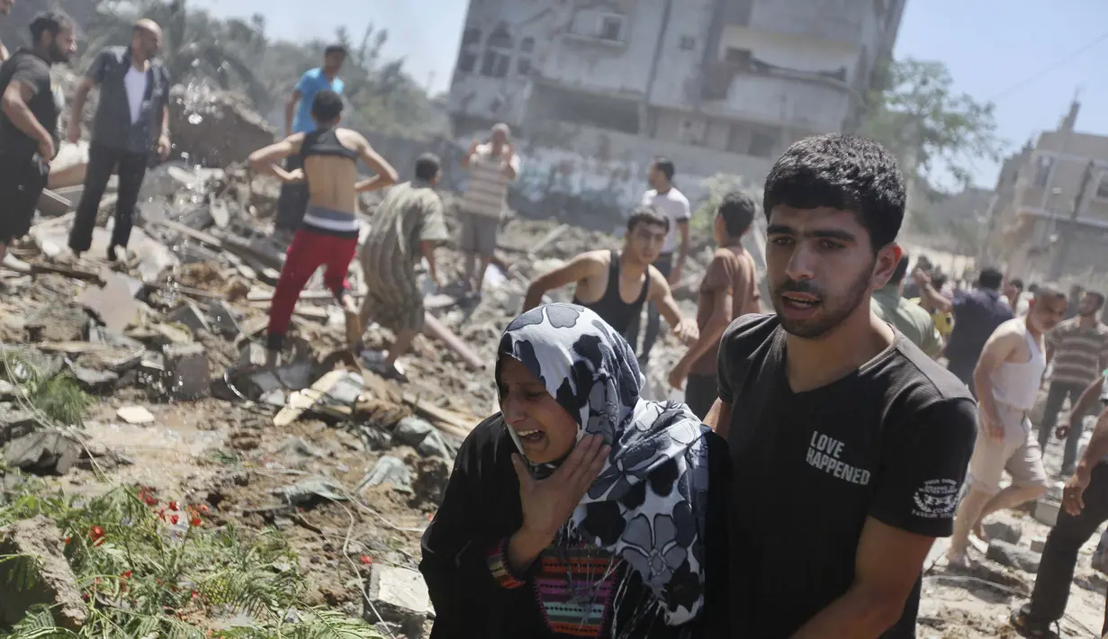 Seorang warga menangis saat dievakuasi polisi ketika terjadi serangan udara Israel di Gaza, Rabu (9/7/14). (REUTERS/Majdi Fathi)