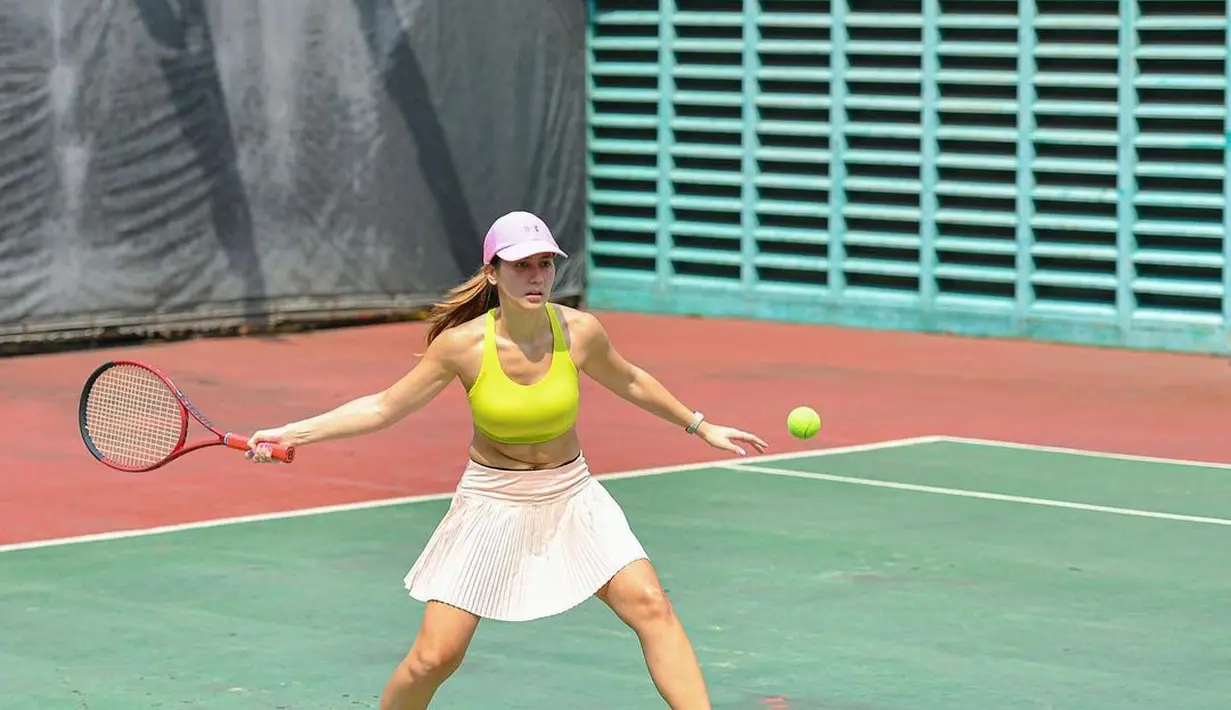 Aksi Pevita Pearce saat berusaha mengembalikan bola tenis dari lawannya dengan mengayunkan raket berwarna merah di tangan kanannya. (Instagram/pevpearce)