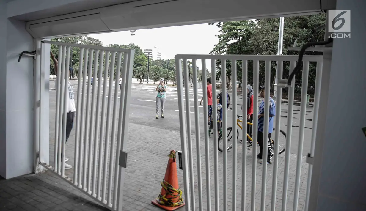 Warga yang berolahraga mengamati kerusakan pintu masuk zona 9 Stadion Utama Gelora Bung Karno, Jakarta, Minggu (18/2). Ratusan Jakmania yang tak memiliki tiket final Piala Presiden 2018 memaksa masuk stadion hingga pintu jebol (Liputan6.com/Faizal Fanani)
