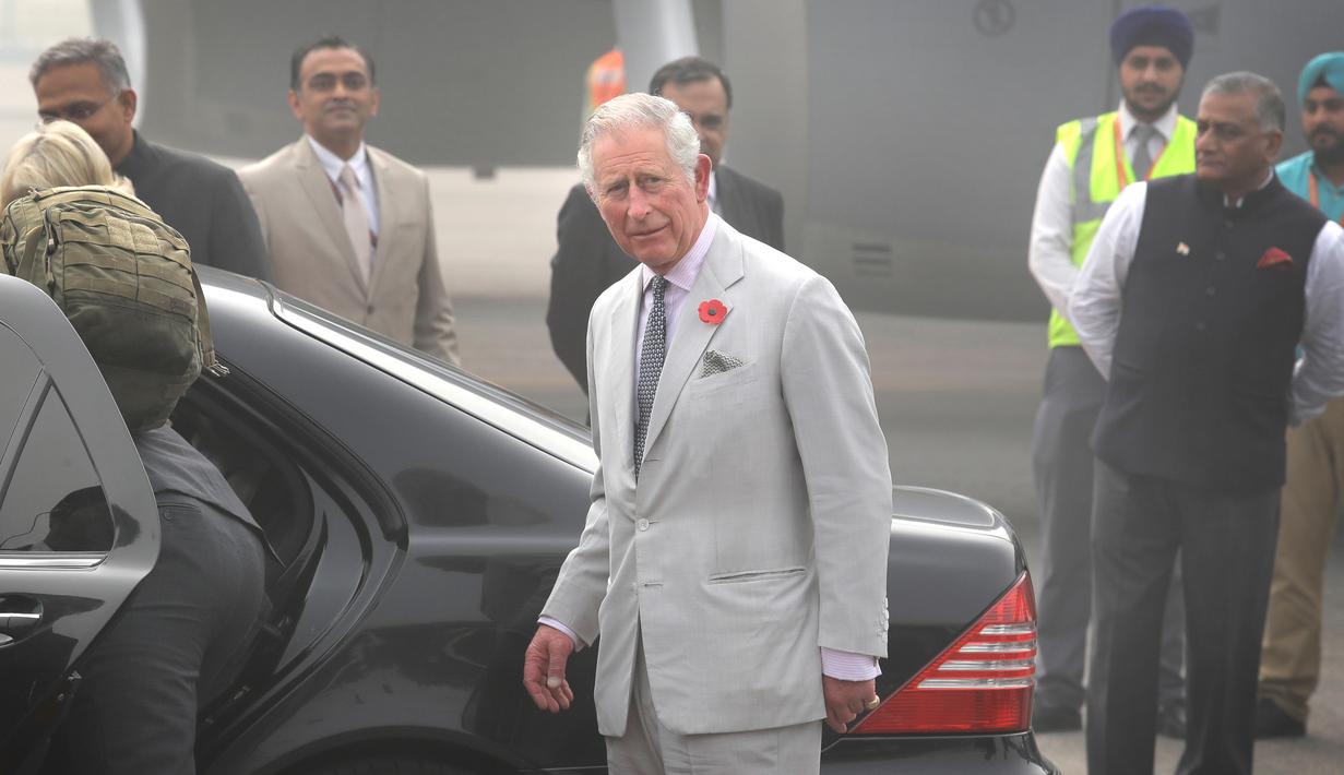 Pangeran Charles bersiap menaiki mobil setelah turun dari sebuah pesawat, bersama sang istri, Camilla di New Delhi yang diselimuti kabut asap, Rabu (8/11). Pasangan dari Kerajaan Inggris itu akan berada di India selama dua hari. (AP Photo/Manish Swarup)