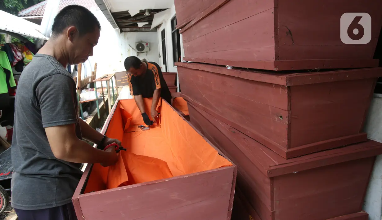 Petugas menyelesaikan pembuatan peti mati khusus jenazah virus corona atau Covid-19 di Dinas Pertamanan dan Pemakaman Jakarta, Sabtu (28/3/2020). Peti mati korban meninggal akibat corona Covid-19 itu dilapisi kantong jenazah dan kain kafan untuk mencegah penyebaran virus. (Liputan6.com/Angga Yuniar)