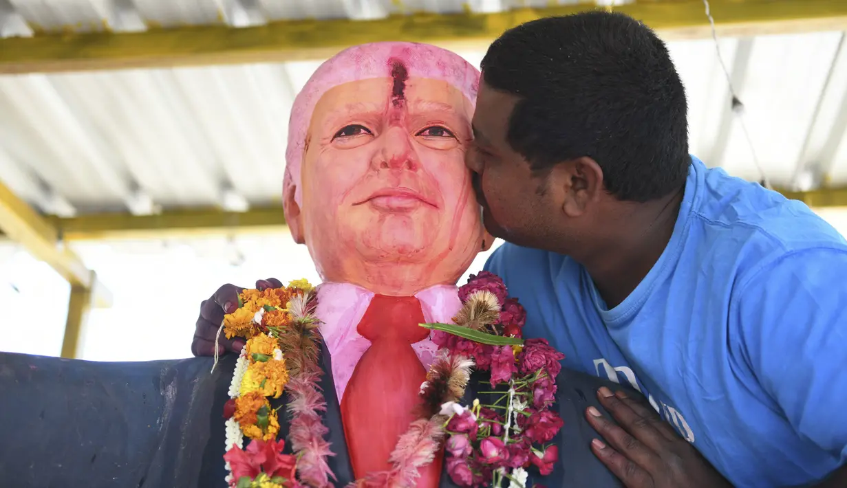 Bussa Krishna (33) mencium patung Presiden AS Donald Trump saat memanjatkan doa  di Desa Konney, Telangana, negara bagian India selatan (14/2/2020). Trump dan istrinya Melania juga akan berkunjung ke rumah Perdana Menteri Narendra Modi, pada 24 Februari. (AFP/Noah Seelam)