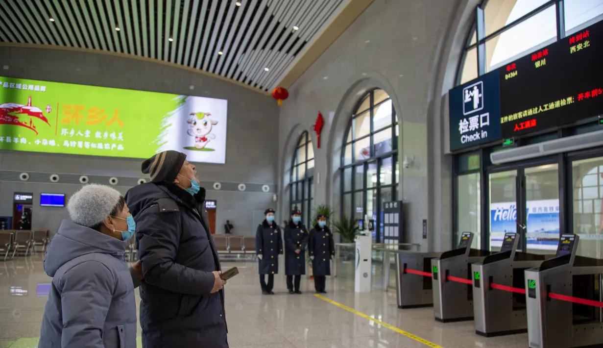 Para penumpang melihat informasi kereta di Stasiun Huanxian, yang berada di sepanjang jalur kereta yang menghubungkan Yinchuan dan Xi'an, di Wilayah Huanxian, Provinsi Gansu, China barat laut (26/12/2020). (Xinhua/Zhang Yongxin)