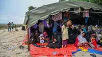 Seratusan pengungsi Rohingya kembali berlabuh Aceh. Hingga Minggu pagi, para pengungsi  ini masih berkumpul di pinggir pantai, setelah turun dari sebuah kapal kayu. (CHAIDEER MAHYUDDIN/AFP)