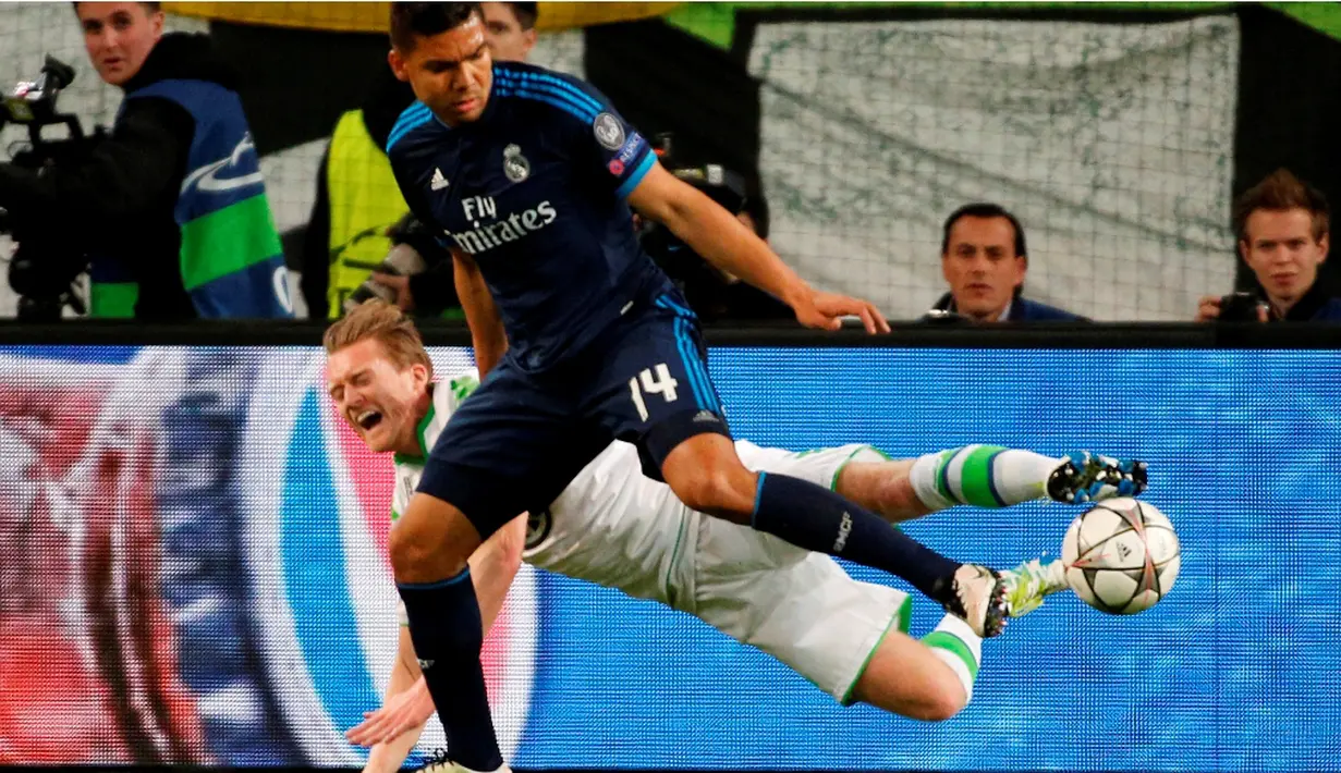 Perebutan bola antara pemain Wolfsburg, Andre Schuerrle, dan pemain Real Madrid, Casemiro, pada leg pertama perempat final Liga Champions di Volkswagen Arena, Wolfsburg, Kamis (7/4/2016) dini hari WIB. (AFP/Odd Andersen)