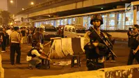 Petugas memasang garis pembatas di lokasi terjadinya ledakan di sekitar Terminal Kampung Melayu, Jakarta, Rabu (24/5). Polisi menemukan potongan tubuh di lokasi ledakan. (Liputan6.com/Angga Yuniar)