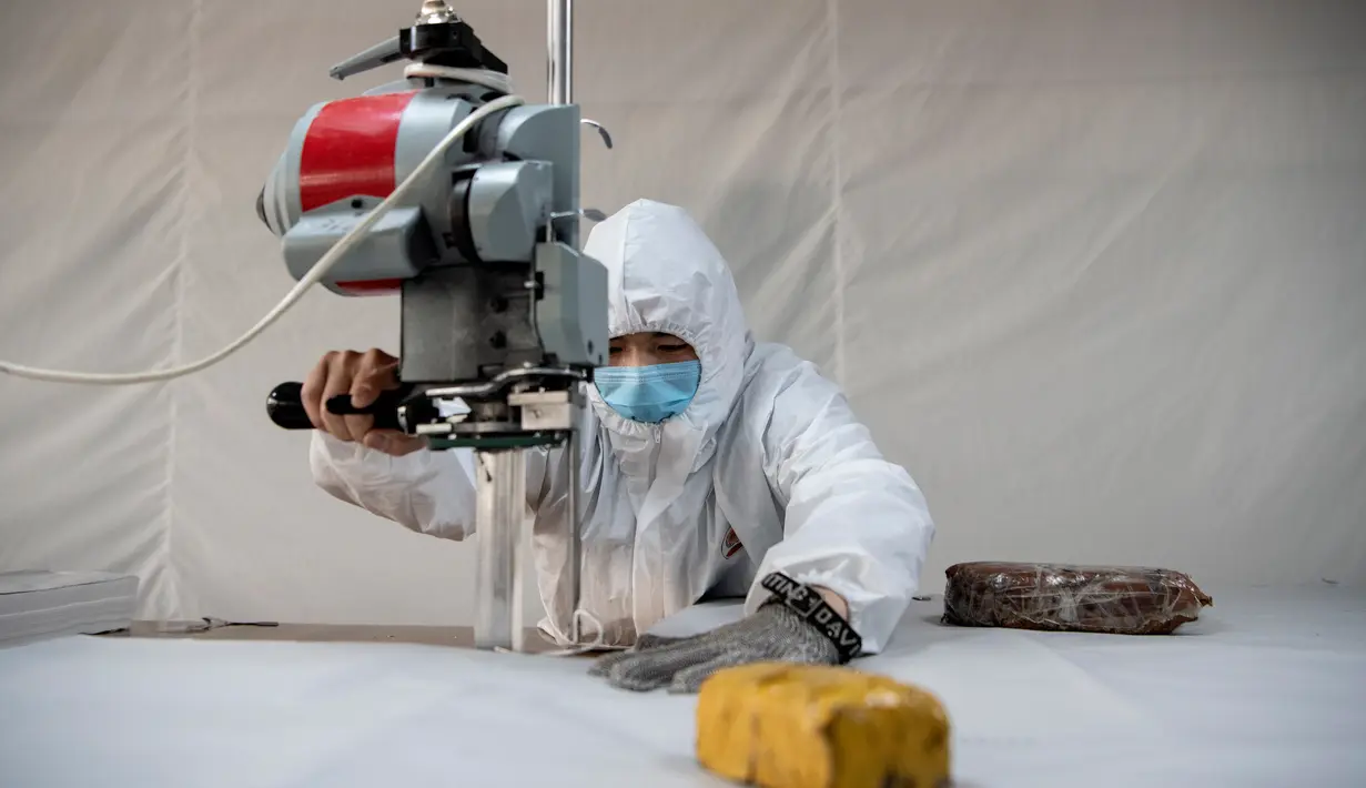 Pekerja memotong bahan untuk digunakan membuat pakaian antivirus di pabrik garmen Zhejiang Ugly Duck Industry, di Wenzhou, 28 Februari 2020. Wabah virus corona di China membuat produsen pakaian itu mulai memproduksi baju hazmat yang banyak diburu orang untuk melindungi dirinya. (NOEL CELIS/AFP)