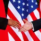 Presiden Amerika Serikat (AS) Donald Trump menggapai tangan Pemimpin Korea Utara, Kim Jong-un untuk bersalaman dalam pertemuan bersejarah di resor Capella, Pulau Sentosa, Singapura, Selasa (12/6). (AP Photo / Evan Vucci)