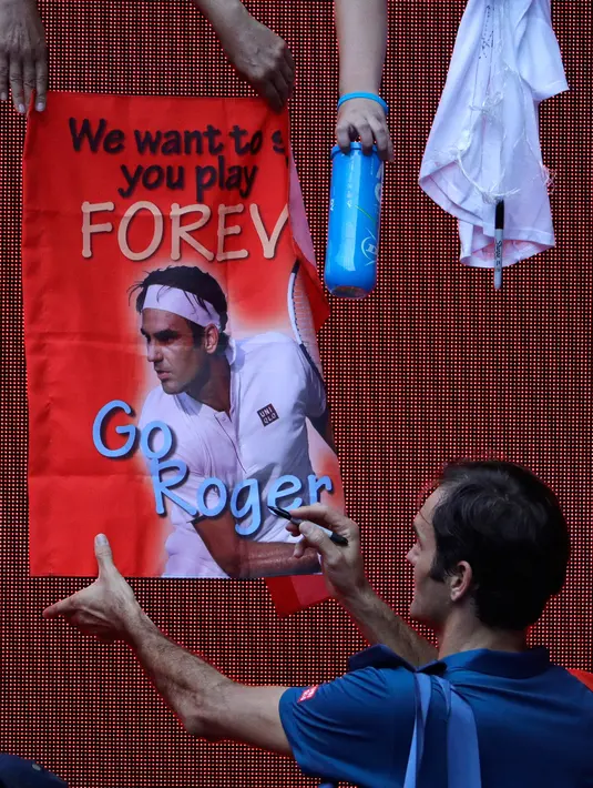 Petenis Swiss, Roger Federer menandatangi poster yang disodorkan penggemarnya setelah mengalahkan Daniel Evans dari Inggris dalam babak kedua  turnamen Australia Terbuka di Melbourne, Rabu (16/1). (AP Photo/Mark Schiefelbein)
