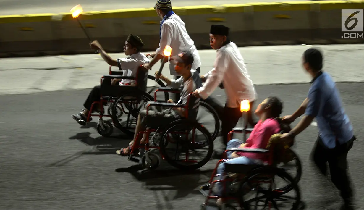 Umat muslim menggunakan kursi roda mengikuti pawai obor menyambut Tahun Baru Islam 1441 H di kawasan Bundaran HI, Jakarta, Sabtu (31/8/2019). Pawai yang diikuti 4000 peserta digelar dalam rangka Jakarta Muharram Festival. (merdeka.com/Imam Bukhori)