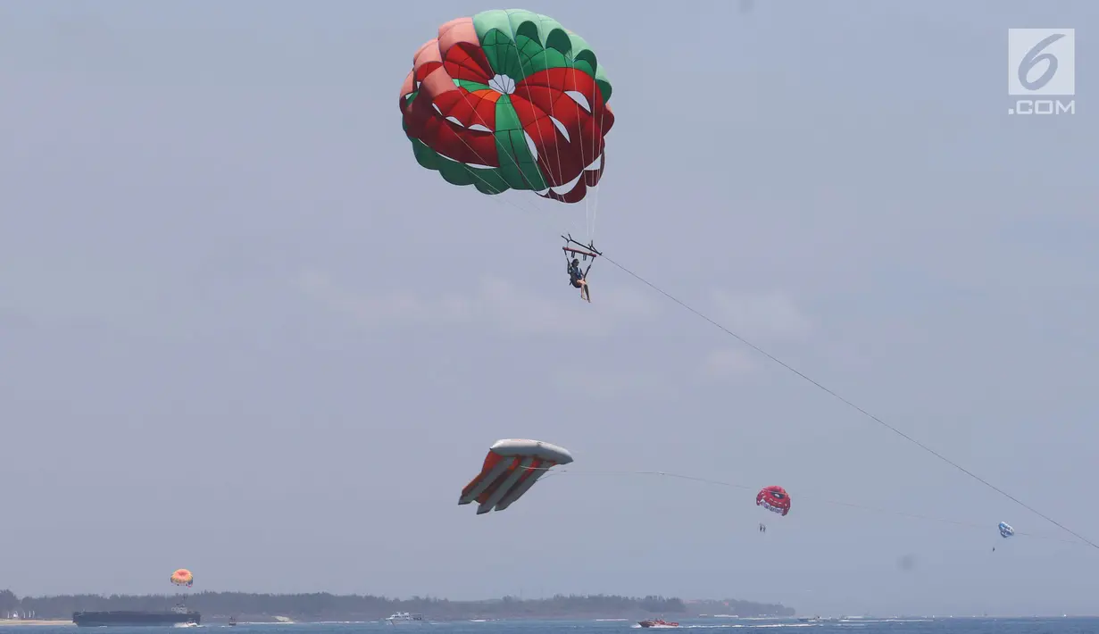 Wisatawan mengikuti permainan Parasailing di pantai Nusa Dua Bali, Rabu (10/10). Kementerian Pariwisata menyiapkan 63 paket wisata untuk turis yang berkunjung selama pertemuan IMF - Bank Dunia Bali 2018. (Liputan6.com/Angga Yuniar)
