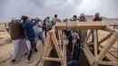 Seorang anggota media turun ke salah satu dari lima makam Firaun kuno yang ditemukan di situs arkeologi Saqqara, Kairo, Mesir(19/3/2022). Menurut Waziri, lima makam yang semuanya dalam kondisi baik itu milik petinggi kerajaan. (AFP/Khaled Desouki)