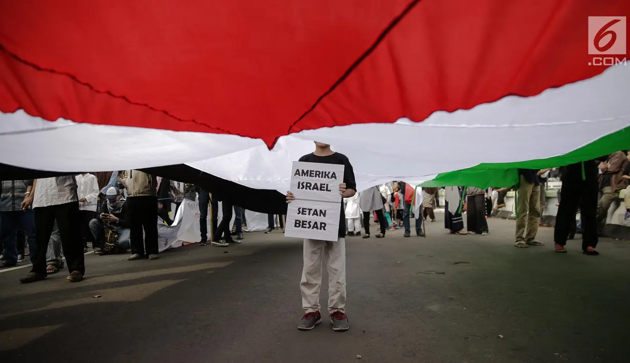 Anak kecil berdiri di tengah bendera Palestina saat aksi di depan Kedubes AS, Jakarta, Jumat (23/6).  Aksi tersebut memperingati Al Quds Day 2017 sebagai dukungan bagi rakyat Palestina dan mengecam kebijakan AS dan Israel. (Liputan6.com/Faizal Fanani)