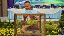 Roy HM Sihombing menegaskan pengungkapan kasus ini penting karena perdagangan ilegal satwa dilindungi merusak keseimbangan ekosistem dan mengancam kelestarian keanekaragaman hayati. Tampak dalam foto, seorang petugas polisi memperlihatkan Ular Sanca Hijau (Morella Viridis) yang disita dari para tersangka penyelundupan hewan yang dilindungi di Markas Besar Kepolisian Daerah Jawa Timur di Surabaya pada Rabu 15 April 2026. (JUNI KRISWANTO/AFP)
