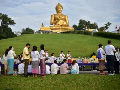 Umat Buddha berkumpul di samping patung Buddha raksasa saat mereka memperingati Hari Makha Bucha di kota Narathiwat, Thailand selatan (6/3/2023). Makha Bucha merupakan salah satu hari raya terpenting bagi para penganut agama Buddha. (AFP/Madaree Tohlala)