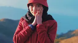 Saat mendaki Gunung Prau, gadis yang berusia 22 tahun ini tidak lupa untuk berfoto dengan pemandangan indah pegunungan. Gayanya tampak imut dengan jaket berwarna merah dan topi dengan warna senada. (Liputan6.com/IG/@arafahrianti)