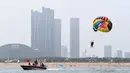 Pengunjung menaiki parasut saat menikmati waktu bersantai di sebuah pantai di Rizhao, Provinsi Shandong, China timur (8/7/2020). (Xinhua/Wang Kai)