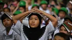 Para pelajar muda meletakkan buku di kepala mereka saat berkumpul di pusat evakuasi yang telah ditentukan di luar gedung sekolah selama latihan gempa bumi di salah satu sekolah dasar di Manila, Filipina pada 11 September 2025. (Ted ALJIBE/AFP)