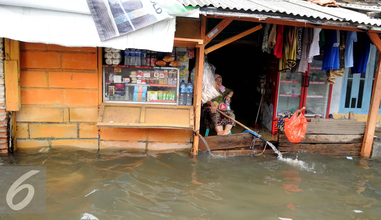 Seorang ibu menguras air yang membanjiri rumahnya dengan menggunakan selang di Kawasan Muara Angke, Jakarta, Rabu (11/1). Banjir ini terjadi hampir setiap hari dalam satu bulan terakhir. (Liputan6.com/Gempur M. Surya)