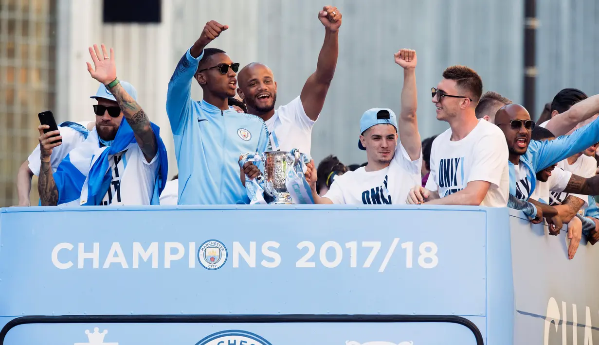 Kapten Manchester City, Vincent Kompany (tengah) bersama rekan setimnya melambaikan tangan dari atas bus beratap terbuka saat melakukan parade merayakan keberhasilan menjadi juara Liga Primer Inggris di Manchester, Senin (14/5). (Anthony Devlin/PA via AP)