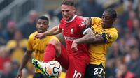 Gelandang Liverpool, Alexis Mac Allister, mendapatkan pengawalan dari gelandang Wolverhampton Wanderers, Jeanricner Bellegarde, pada laga pekan kelima Premier League 2023/2024 yang berlangsung di Molineux Stadium, Sabtu (16/9/2023) malam WIB. (AFP/Adrian Dennis)