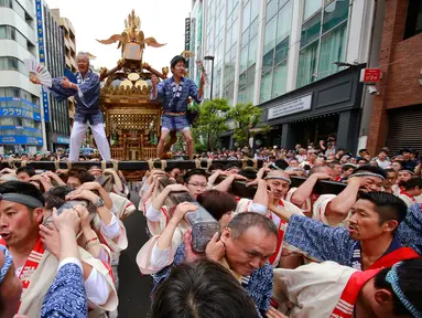 Peserta mengenakan pakaian tradisional mengarak kuil portabel saat merayakan Festival Kanda Matsuri di Tokyo, Minggu (14/5). Kanda Matsuri atau Festival Kanda, merupakan salah satu festival tiga Shinto besar Tokyo. (AP Photo / Shizuo Kambayashi)