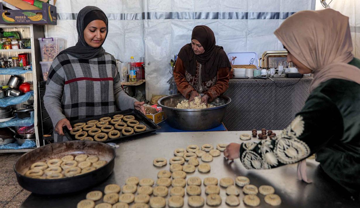 Kaak merujuk pada jenis roti populer yang biasa di kosumsi di seluruh Timur Tengah (Palestina, Lebanon, Suriah, Yordania). Tampak dalam foto, para wanita menyiapkan biskuit tradisional "kaak" yang berbentuk cincin menjelang Idul Fitri, hari raya yang menandai berakhirnya bulan puasa suci Ramadan, di Kota Gaza pada 16 Maret 2026. (Omar AL-QATTAA/AFP)