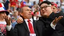 Peniru Presiden Rusia, Vladimir Putin dan pemimpin Korea Utara, Kim Jong-un berpose selama menyaksikan laga penyisihan Grup A Piala Dunia 2018 antara Uruguay vs Rusia di Samara Arena, Senin (25/6). Uruguay berhasil melumat Rusia 3-0. (AFP/EMMANUEL DUNAND)