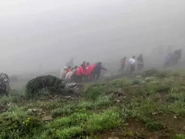 Gambar ini diambil dari rekaman video selebaran yang dirilis oleh Bulan Sabit Merah Iran pada 20 Mei 2024 yang menunjukkan tim penyelamat menemukan jenazah di lokasi jatuhnya helikopter Presiden Ebrahim Raisi di daerah pegunungan yang diselimuti kabut di barat laut Iran. (Iranian Red Crescent / AFP)