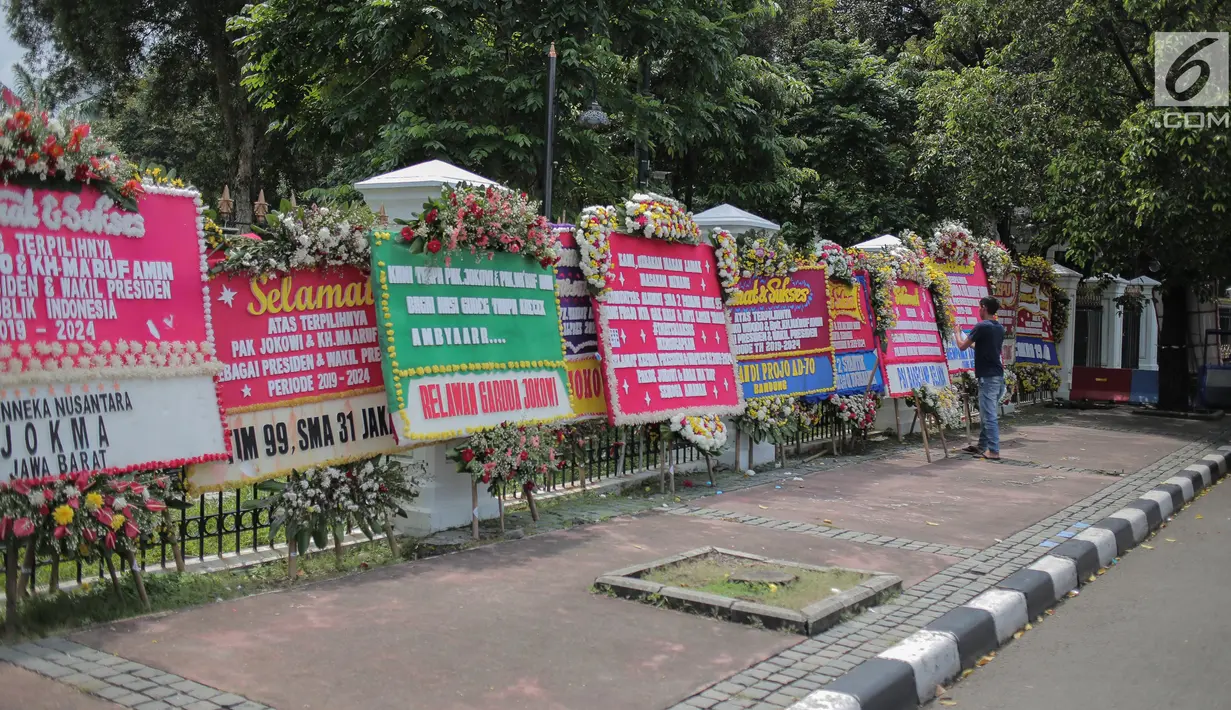 Pekerja meletakkan karangan bunga bertuliskan ucapan selamat untuk Joko Widodo dan Ma'ruf Amin di depan pagar gedung Sekretariat Negara, Jakarta, Senin (22/4). Karangan bunga dari pendukung Jokowi-Ma'ruf tersebut ditujukan atas kemenangan pasangan itu pada Pilpres 2019. (Liputan6.com/Faizal Fanani)
