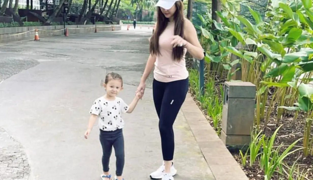 Kali ini, Aura memadukan tank top pink dan celana legging warna hitam. Gayanya ini dilengkapi dengan sneakers putih dan topi putih. (Instagram/aurakasih).