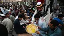 Relawan menyajikan makanan berbuka puasa kepada muslim Pakistan di sepanjang jalan di Rawalpindi pada 7 Mei 2019. Ketika bulan Ramadan mulai di Pakistan, banyak masyarakat muslim memanfaatkan buka puasa gratis yang disponsori oleh badan-badan amal dan orang-orang kaya. (RIZWAN TABASSUM / AFP)