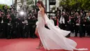 Model Alessandra Ambrosio berjalan di karpet merah saat menghadiri pemutaran film "The Dead Don't Die" selama Festival Film Cannes ke-72 di Prancis (14/5/2019). Model cantik asal Brasil ini tampil memesona dengan gaun putih sutra transparan Ralph & Russo. (AFP Photo/ValeryHache)