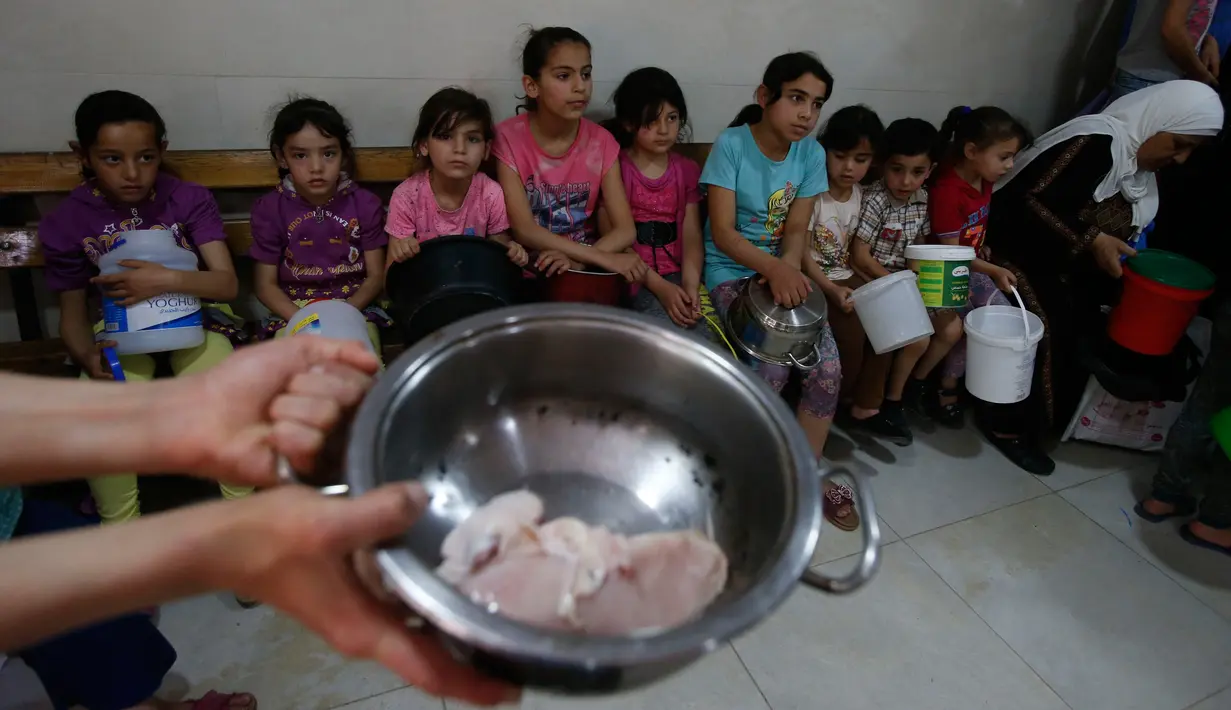 Anak-anak Palestina mengantre untuk makanan buka puasa gratis di sebuah dapur amal, kota Hebron, Tepi Barat, Minggu (20/5). Dapur amal yang dikelola Wakaf Islam itu dinilai sangat membantu dalam mencukupi gizi selama bulan Ramadan tiba. (AFP/HAZEM BADER)