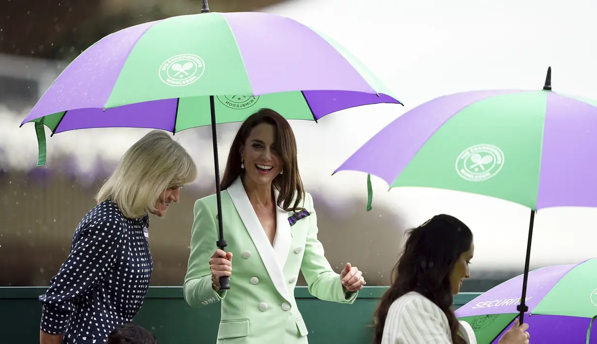 Blazernya serasi dengan warna hijau dari payung Wimbledon yang harus dipegangnya sebentar saat ia, seperti penggemar lainnya, berlindung dari hujan musim semi di London. (Zac Goodwin/Pool Photo via AP)