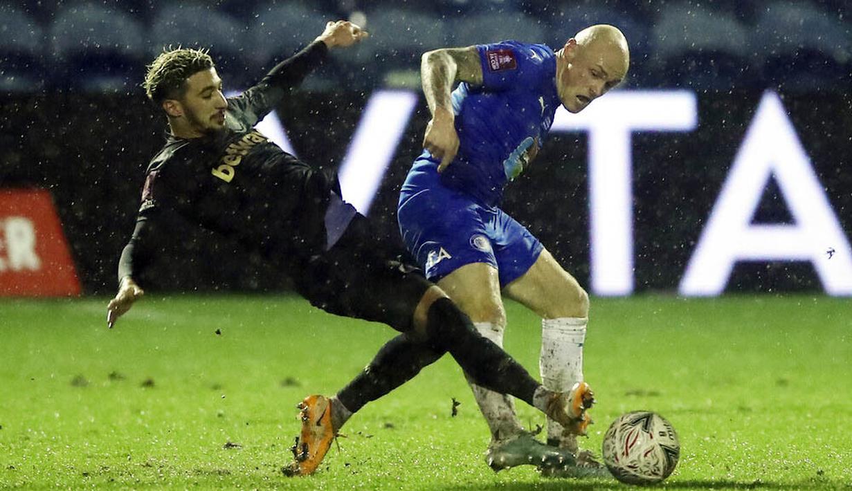 Pemain Stockport County, Sam Minihan, berebut bola dengan pemain West Ham United, Said Banrahma, pada laga Piala FA di Stadion Edgeley Park, Senin (11/1/2021). West Ham United menang dengan skor tipis 1-0. (Martin Rickett/Pool via AP)