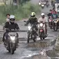 Pengendara motor melintasi jalan rusak dan berlubang di Jalan Tegar Beriman, Cibinong, Bogor, Minggu (31/5/2020). Sudah berbulan-bulan akses yang dikenal sebagai jalan Pemda Cibinong ini sangat memprihatinkan hingga sering menyebabkan kecelakaan terlebih saat musim hujan. (merdeka.com/Iqbal Nugroho)