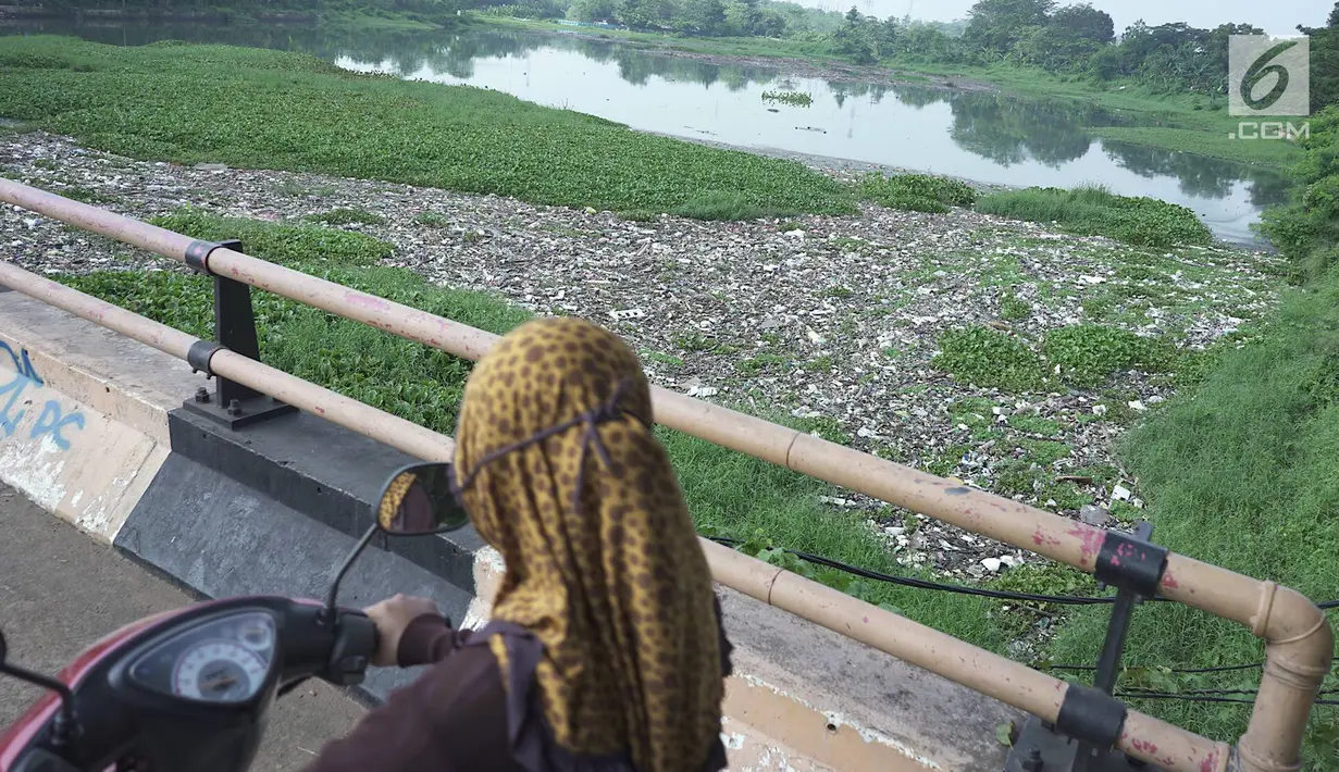 Pengendara sepeda motor melintasi Setu Pengarengan yang dipenuhi sampah dan eceng gondok di Depok, Jawa Barat, Selasa (7/5/2019). Keberadaan sampah dan eceng gondok di Setu Pengarengan menimbukan kesan kumuh. (Liputan6.com/Immanuel Antonius)