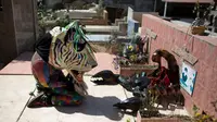 Seorang pria mengenakan kostum dan topeng binatang berdoa di makam kerabatnya saat perayaan tradisional di Naiguata, Venezuela (31/5). Sejumlah orang kerasukan dan menari selama festival yang dikenal Dancing Devils ini di Naiguata. (AP/Arian Cubillos)