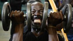 Seorang pria mengangkat beban saat berolahraga di gym Kaloleni, di Nairobi, Kenya (9/1).  (AFP Photo/Simon Maina)