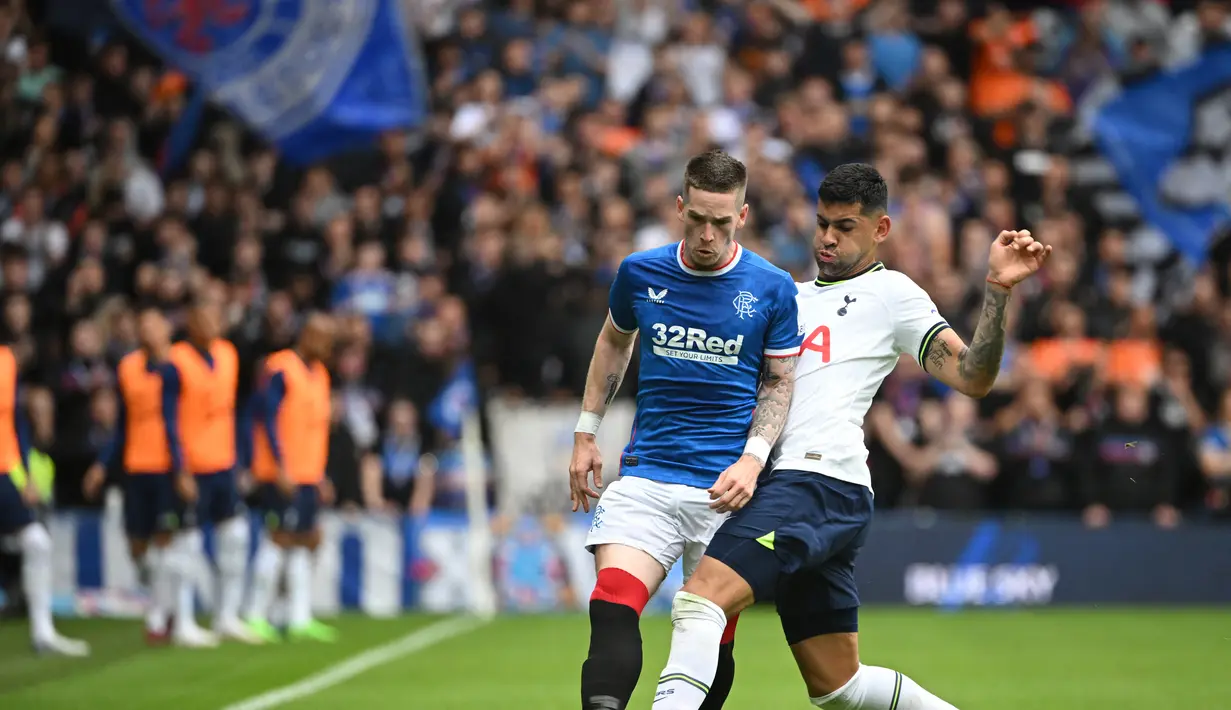 Gelandang Rangers, Ryan Kent (kiri) berebut bola dengan bek Tottenham Hotspur, Cristian Romero dalam pertandingan persahabatan di Stadion Ibrox di Glasgow (23/7/2022). Tottenham menang tipis atas Rangers 2-1. (AFP Photo/Andy Buchanan)