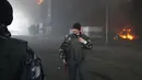 Prajurit Ukraina berjalan saat api dan asap membubung di atas sebuah bangunan setelah penembakan di Kiev, Ukraina, Kamis (3/3/2022). Rusia telah meluncurkan serangan jarak jauh ke Ukraina, menghantam kota dan pangkalan dengan serangan udara atau penembakan. (AP Photo/Efrem Lukatsky)