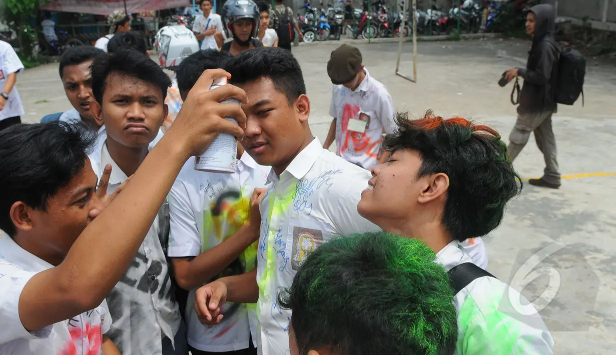 Siswa SMK Kemala Bhayangkari 1 Jakarta, mencoret rambut temannya dengan cat semprot usai mengikuti Ujian Nasional (UN), Kamis (16/4/2015). Aksi tersebut dilakukan sebagai bentuk kegembiraan usai mengikuti UN. (Liputan6.com/Herman Zakharia)