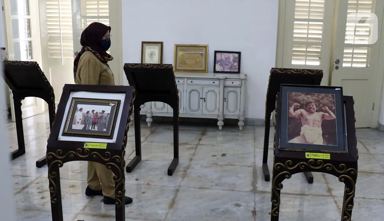 Ibu Endang dari Unit Pengelola Gedung Pertunjukan dan Seni Budaya (UP-GPSB) Dinas Pariwisata dan Budaya Pemprov DKI Jakarta menunjukkan beberapa koleksi foto-foto lawas seniman betawi, Benyamin Suaeb di Gedung Taman Benyamin Suaeb, Jakarta, Selasa (23/6/2020). (Liputan6.com/Helmi Fithriansyah)
